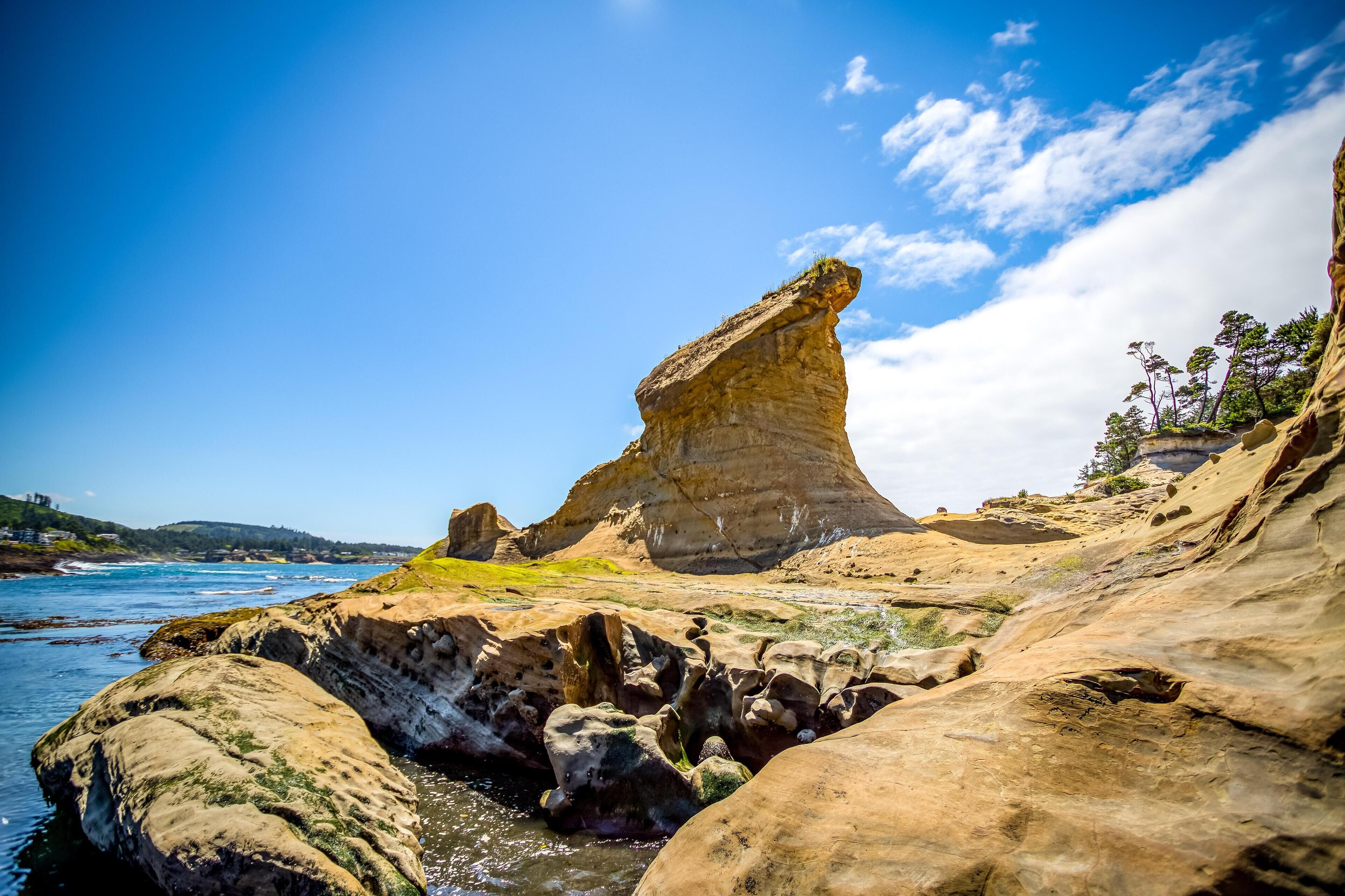 A coastal landscape with prominent rock formations and a clear blue sky.