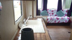 Une petite cuisine équipée d’un évier, d’une bouilloire et d’une plaque de cuisson portable.
