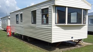 Une maison mobile comprenant une chambre, une petite cuisine et une véranda.