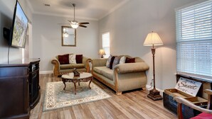 A living room with two sofas, a coffee table, a television, and a ceiling fan.