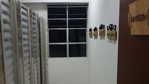 Un pasillo con una puerta de madera, una ventana con persianas y un tapete azul en el suelo.