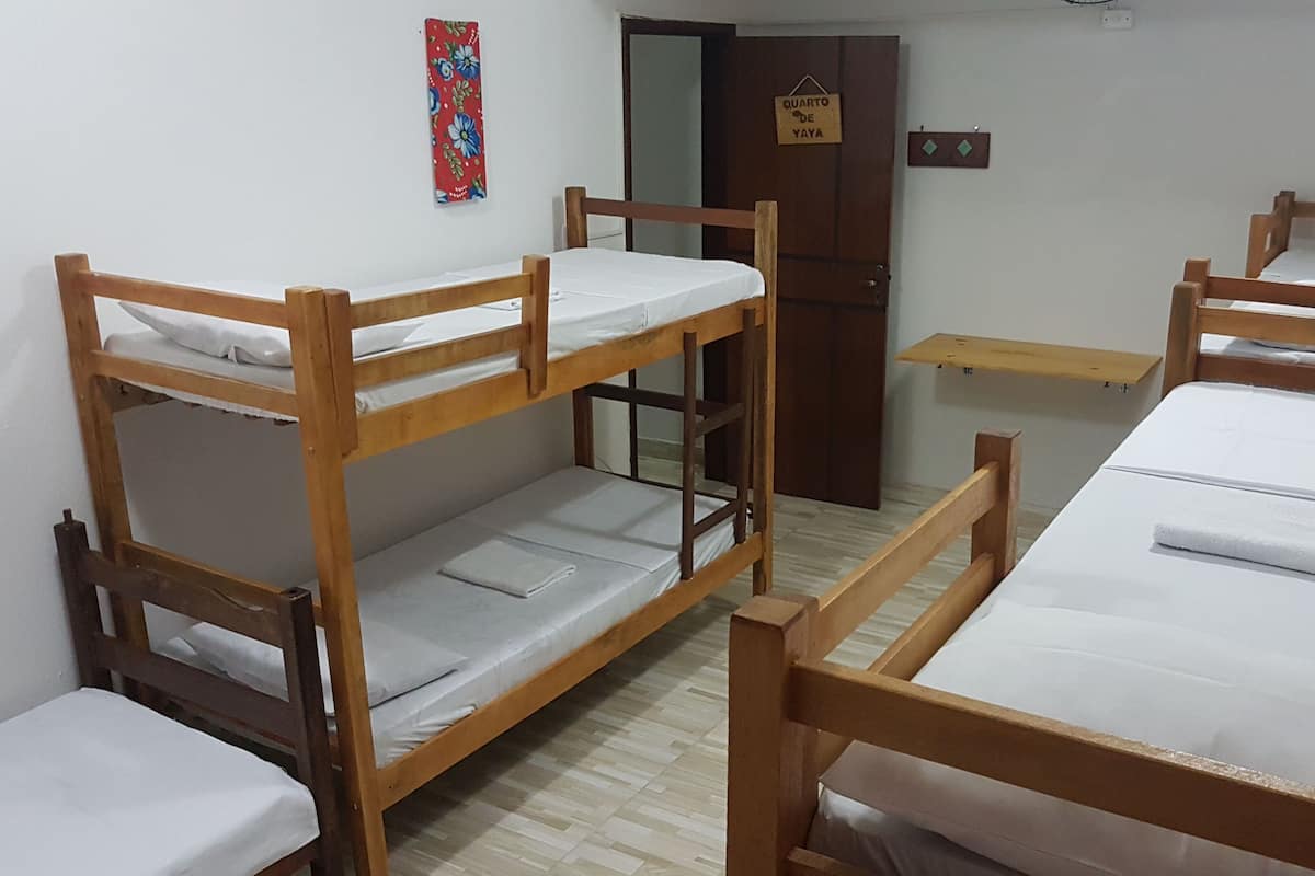 Un dormitorio con cuatro literas, una puerta de madera, un estante pequeño y un cartel en la pared.