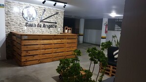 Un mostrador de recepción con un fondo de pared de piedra y un cartel con indicaciones.