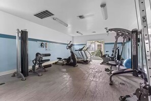 A gym with cardio machines, weightlifting equipment, and a mirrored wall.