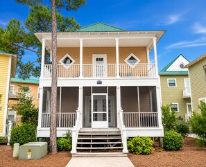A two-story house with a front porch, a balcony on the upper floor, and a mailbox.