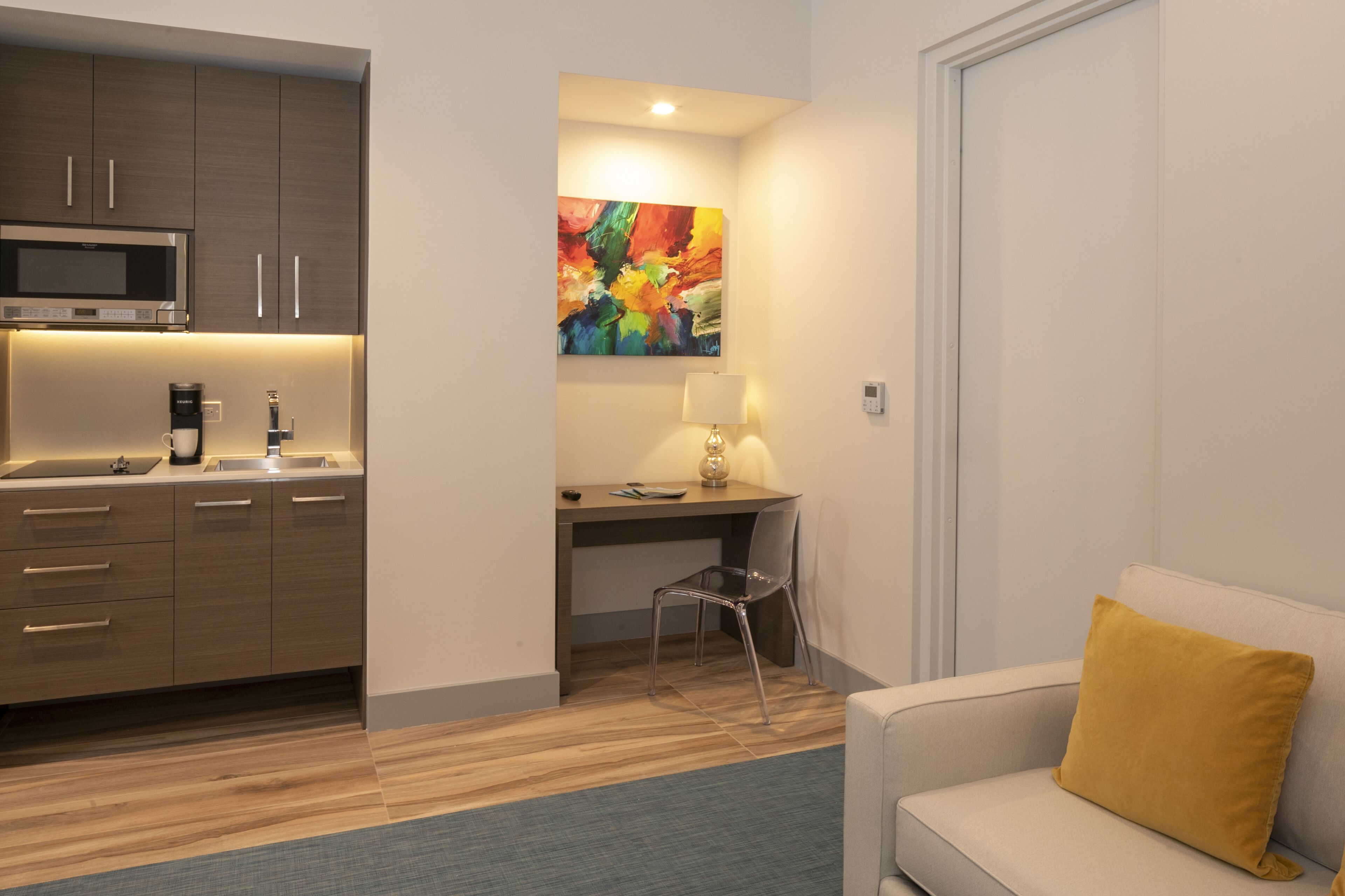 A modern kitchen with a microwave, coffee maker, and a dining area with a chair and table.