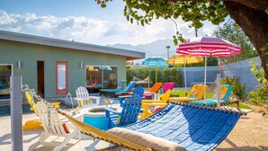 Ein Poolbereich mit Hängematte, bunten Liegestühlen und Sonnenschirmen.