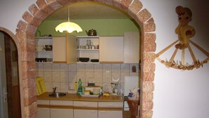 A kitchen with white cabinets, a tiled backsplash, and a hanging light fixture.