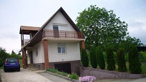 A two-story house with a balcony, a driveway, and a car parked in front.