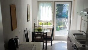 A compact kitchen with a dining area, a window with a view, and a kitchenette. - Fewo Mayer am Bodensee (Friedrichshafen)