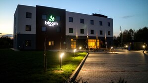Un hotel moderno con un llamativo letrero que dice 'bloom', entrada pavimentada e iluminación exterior.
