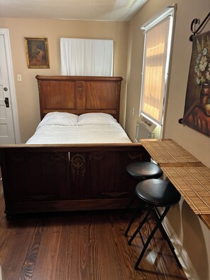 A bedroom with a wooden bed, a nightstand, a chair, and a painting on the wall. - 1930s Rear Unit, 3 miles to DT, Walk 2 Trinity U, Private Entrance (San Antonio)