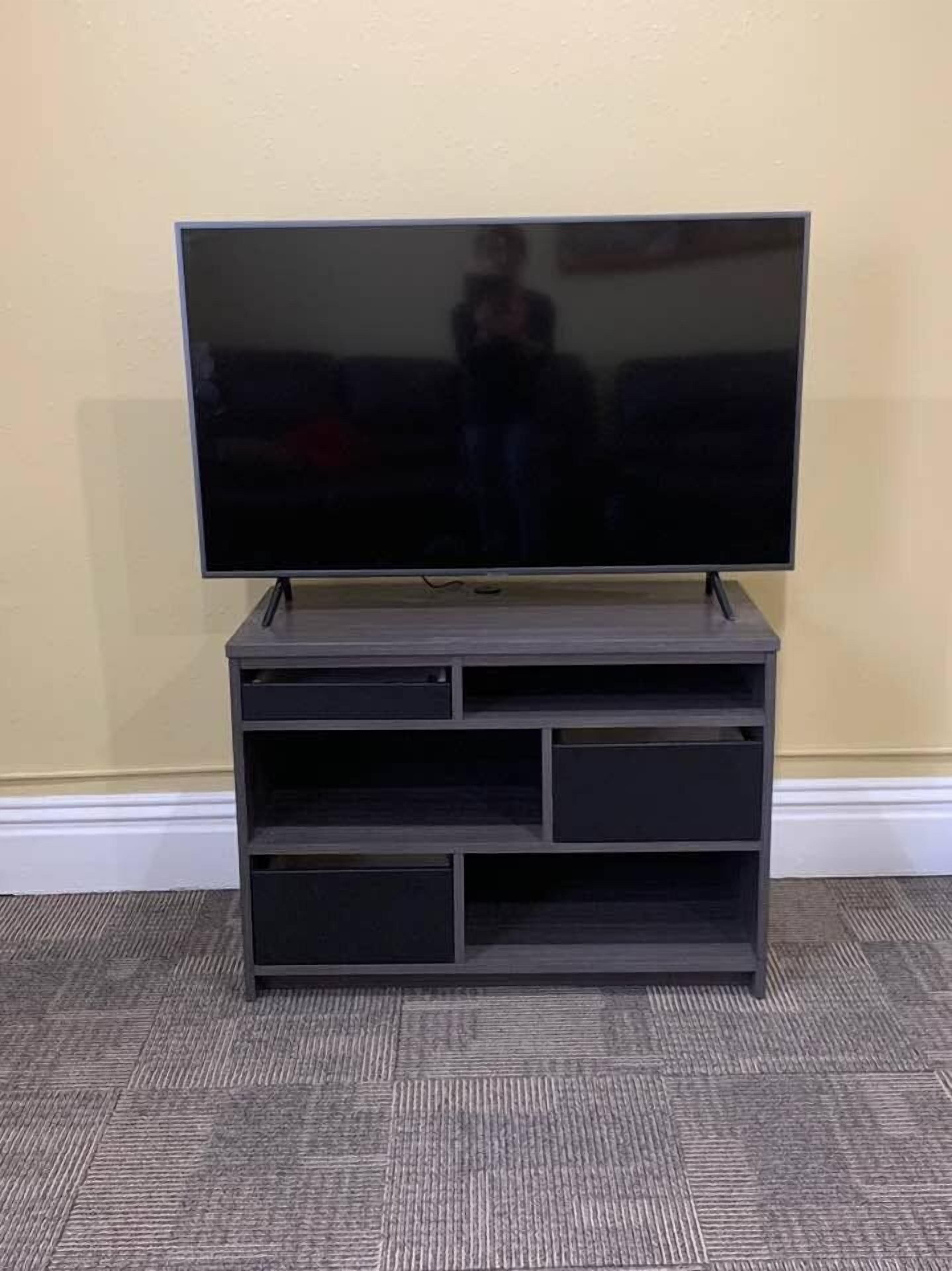 A flat-screen TV on a dark wooden entertainment center with multiple shelves.