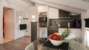 Een moderne keuken met witte kastjes, een zwart aanrecht en een schaal fruit op de tafel.