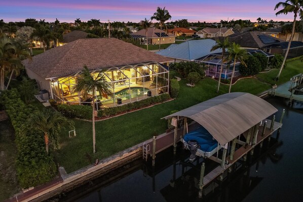 A house with a swimming pool, a covered dock, and a well-maintained lawn.