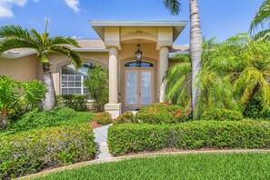 A house with a well-maintained garden, a covered entryway, and a front door.