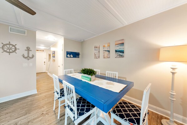 Et spiseområde med et blåt bord, hvide stole og maritim indretning.