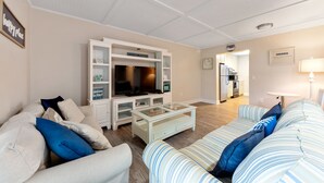 Un salon avec un téléviseur, un canapé et une table basse.