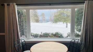 A room with a round wooden table and two chairs with cushioned seats.