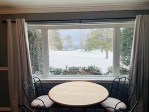 A room with a round wooden table and two chairs with cushioned seats.