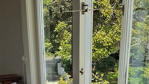 Ein Schlafzimmer mit einem Bett, einem Fenster und Blick auf einen Garten.