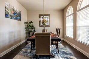 Enjoy meals in this dining area with a long table and comfortable seating, surrounded by natural light and a beautiful view.
