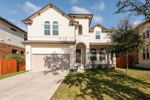 A two-story house with a garage, a brick foundation, and a well-maintained lawn.
