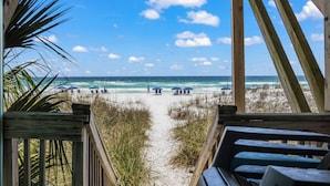 A wooden deck leading to a beach with umbrellas and people in the distance. - BEACHFRONT Beach Vacation! Eat Breakfast While You Watch Dolphins!! (Destin)