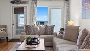 A living room with a sofa, a coffee table, and a view of the sea through large windows. - BEACHFRONT Beach Vacation! Eat Breakfast While You Watch Dolphins!! (Destin)