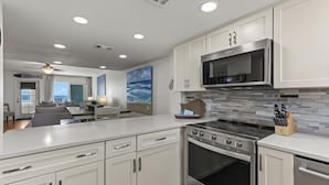 A modern kitchen with white cabinetry, a stainless steel range, and a microwave. - BEACHFRONT Beach Vacation! Eat Breakfast While You Watch Dolphins!! (Destin)