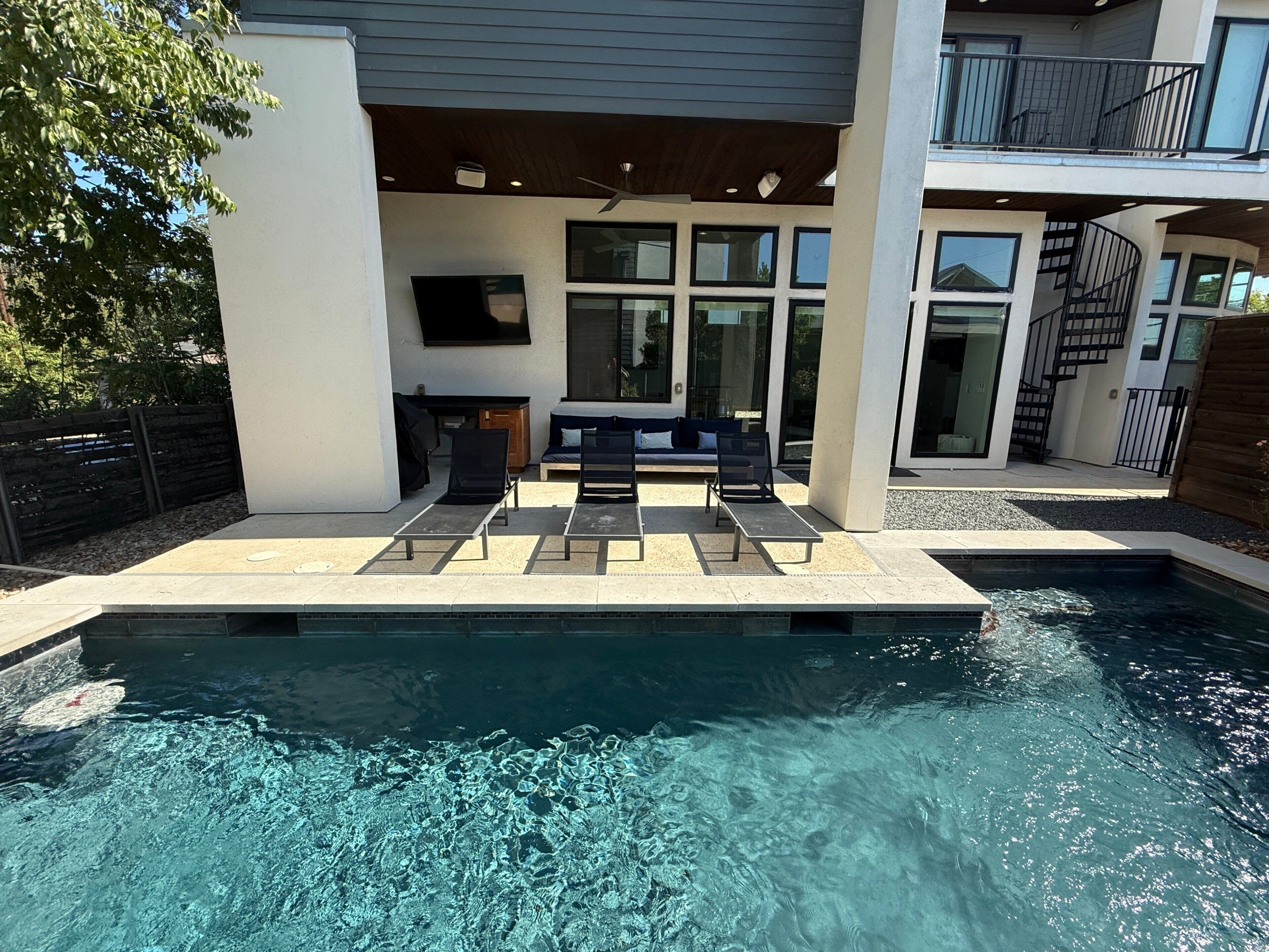 Uma área moderna de piscina ao ar livre com espreguiçadeiras e um espaço de estar integrado.