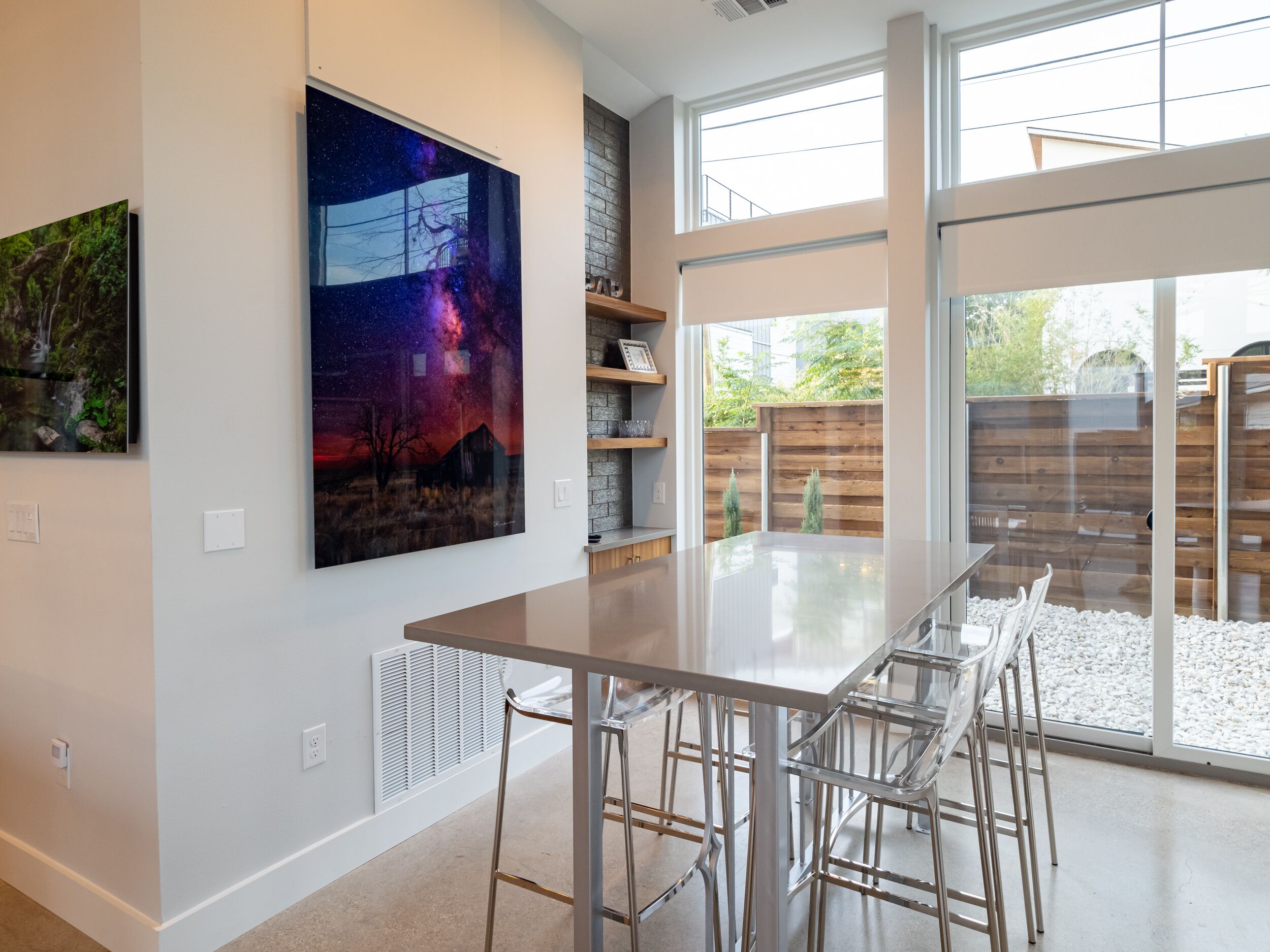 Una cocina moderna con un ventanal grande, una mesa de comedor con sillas y un cuadro de gran tamaño en la pared.