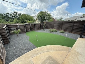 Ein Garten mit Kunstgrasanlage, Holzzaun und einem kleinen Gartenbeet.