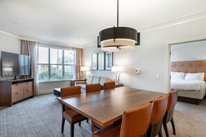 A hotel room with a large dining table, a TV, a bed, and a window with curtains. - Phoenix | Golf Retreat | Pool & Spa | 2BR Villa (Phoenix)