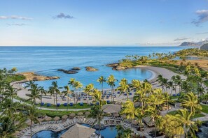Un complexe hôtelier doté d’une piscine, d’une plage et de palmiers.