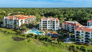 A resort with multiple buildings, a swimming pool, and surrounding greenery.