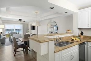 A modern kitchen with granite countertops, a built-in sink, and a dining area with a view.