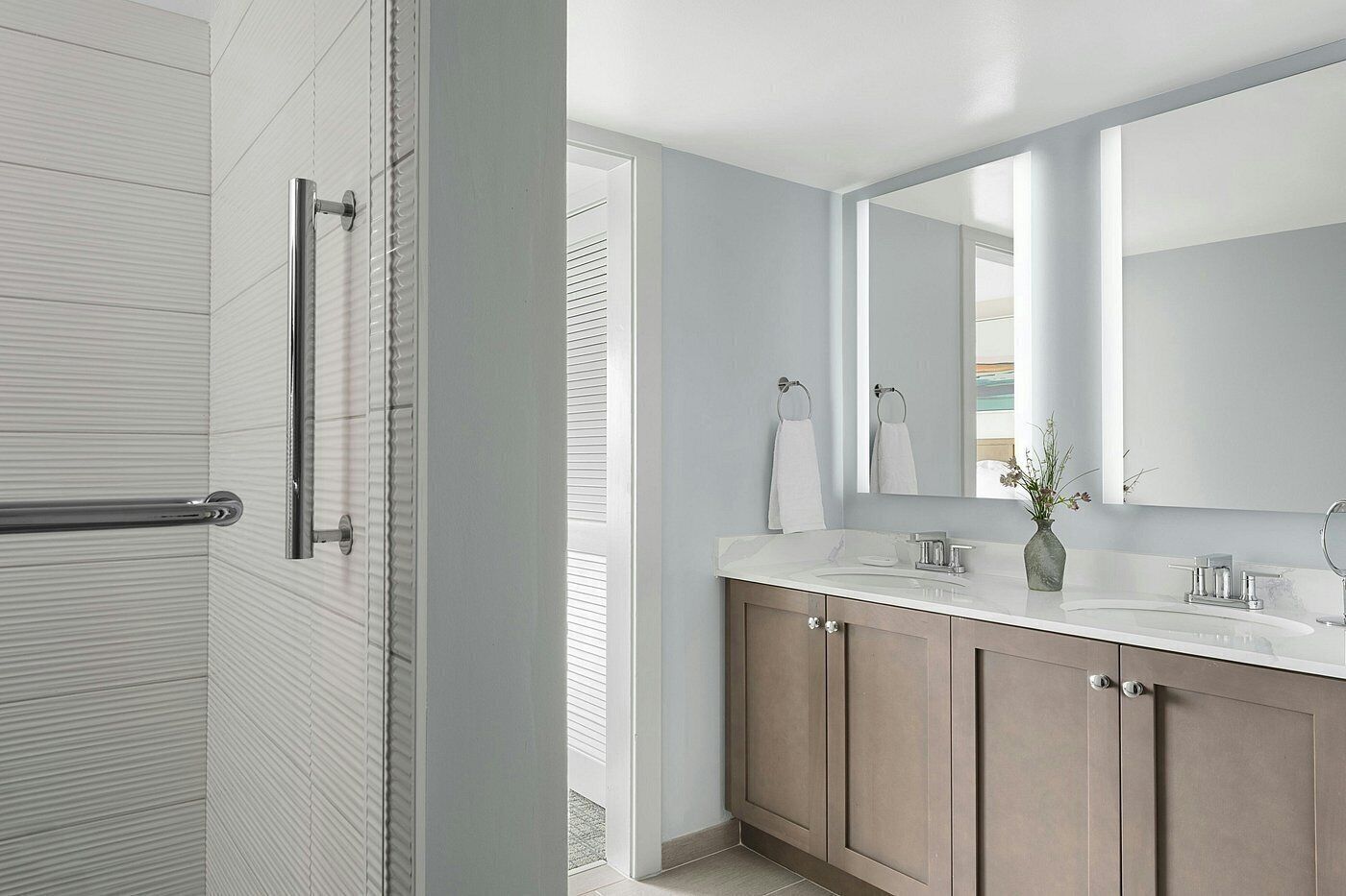 A modern bathroom with a shower, a large mirror, and a vanity with a sink.