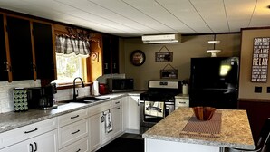 Een moderne keuken met witte kasten, een granieten aanrechtblad, een inbouwmagnetron en een groot eiland met barstoelen.