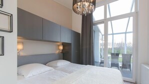 Un dormitorio moderno con una cama grande, una araña y vistas del exterior a través de amplios ventanales.