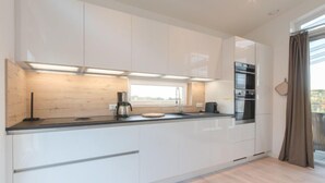 Una cocina moderna con armarios blancos, encimera negra y horno integrado.