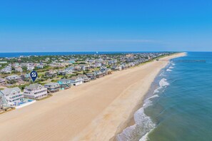 Une ville côtière dotée de propriétés en bord de mer, d’une jetée qui s’avance dans l’océan et d’un ciel dégagé.
