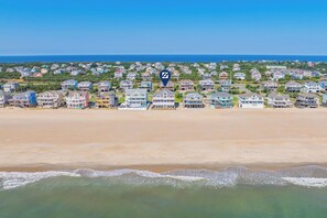 Une zone résidentielle côtière avec des propriétés donnant sur la plage, un ciel dégagé et une mer calme.