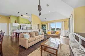 A spacious living area with a sofa, a coffee table, and a dining area with chairs.