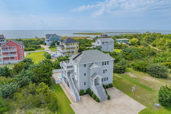 A coastal residential area with multiple houses, a swimming pool, and a view of the sea.