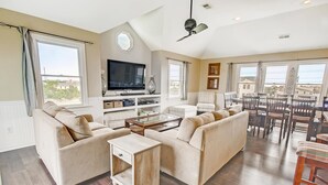 A spacious living room with a large TV, comfortable seating, and a dining area with wooden furniture. - Soundside Home w/ Private Pool, Hot Tub, Game Room, Cabana, Community Boat Ramp (Salvo)