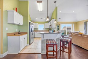 A spacious kitchen with white cabinetry, a central island, and a view to the outside.