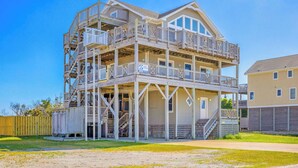 A two-story building with a balcony and a covered area, possibly a beach house. - Oceanview w/ Private Pool, Hot Tub, Game Room, and Wet Bar. Surf's Up Rodanthe! (Rodanthe)