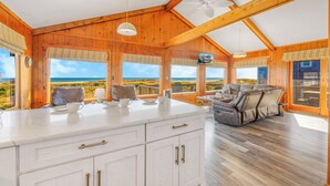 A spacious room with a large wooden ceiling, a white marble island with a sink, and a leather sofa.