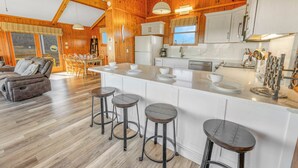A spacious kitchen with a central island, wooden beams, and a dining area with a sofa and chairs.